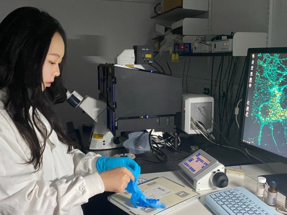 Chloe Park putting on gloves in a lab near a computer
