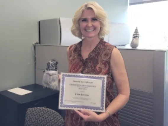 Lisa Arrotta smiling while holding up award