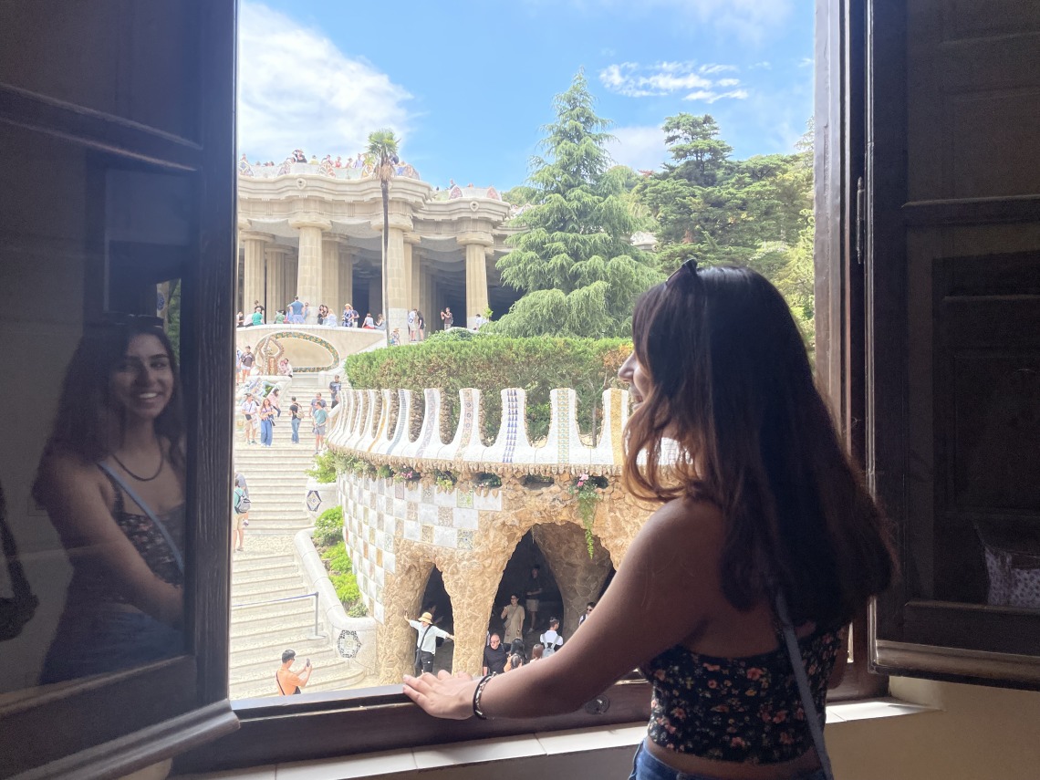 Grace Parekh looking out a window onto Spanish architecture